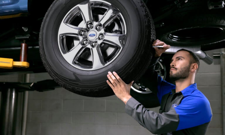 A Ford technician inspecting a tire