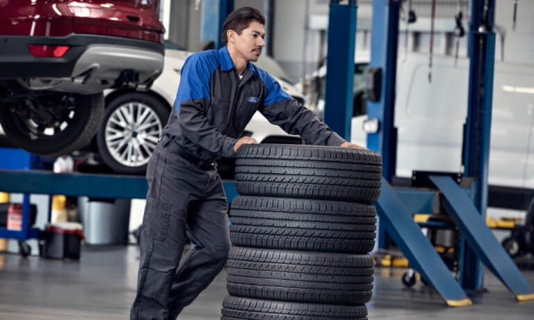 Ford technician moving tires across the shop