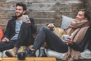 Man and woman drinking coffee with a pug.