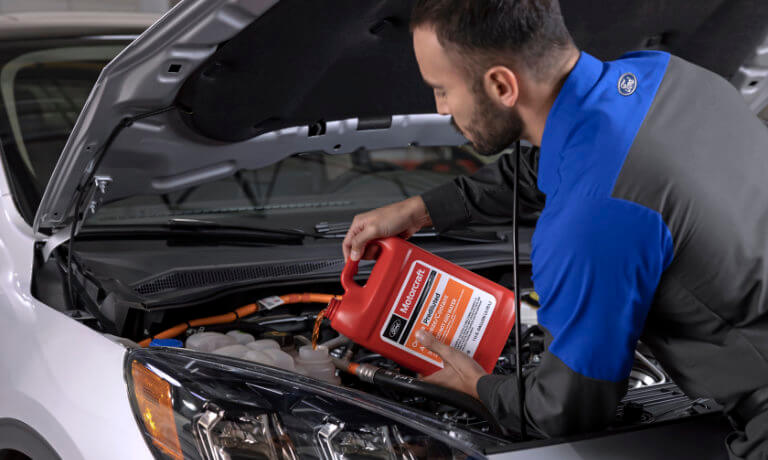 Ford technician pouring oil into a car